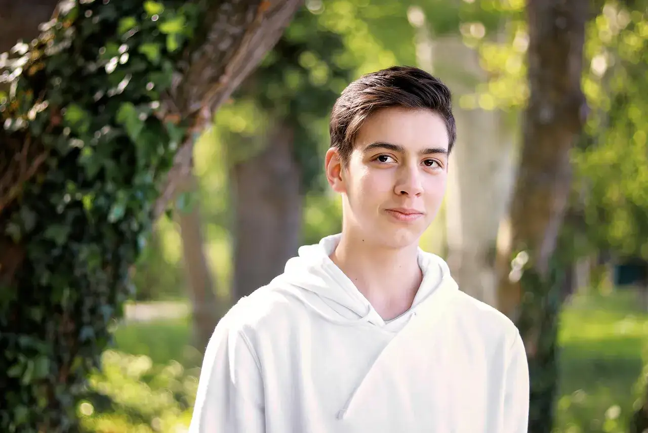 Ung kille i vit hoodie utomhus. Enkelt att ta bra bilder med iPhone i naturen.