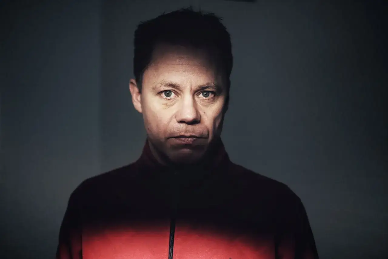 Knut Koivisto, en man med intensiv blick, kl&auml;dd i en r&ouml;d jacka. Ljuset faller dramatiskt &ouml;ver hans ansikte.