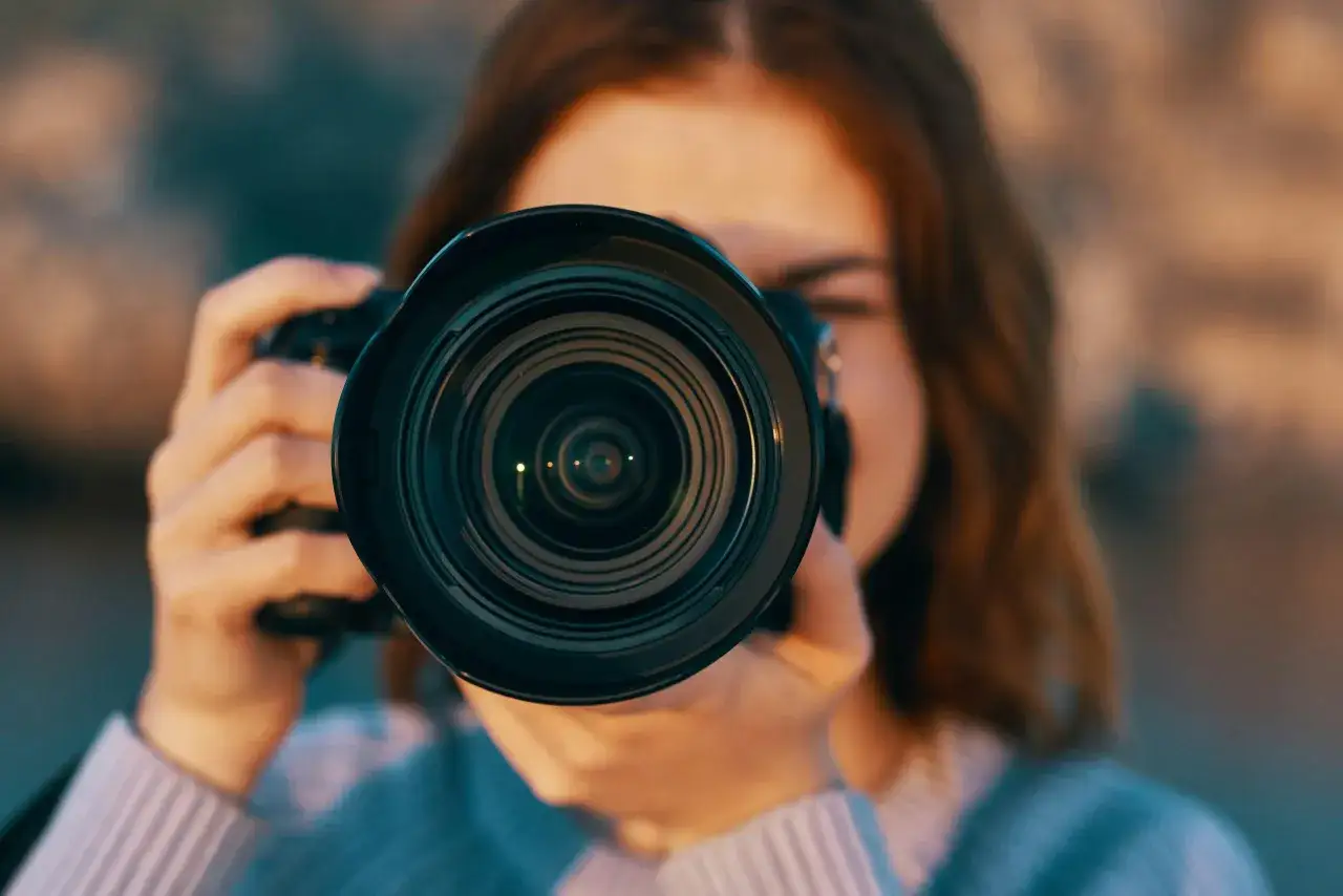 En person håller upp en kamera och tittar genom sökaren. Linsen är i förgrunden, och det är tydligt vad betyder fokus för fotografen.