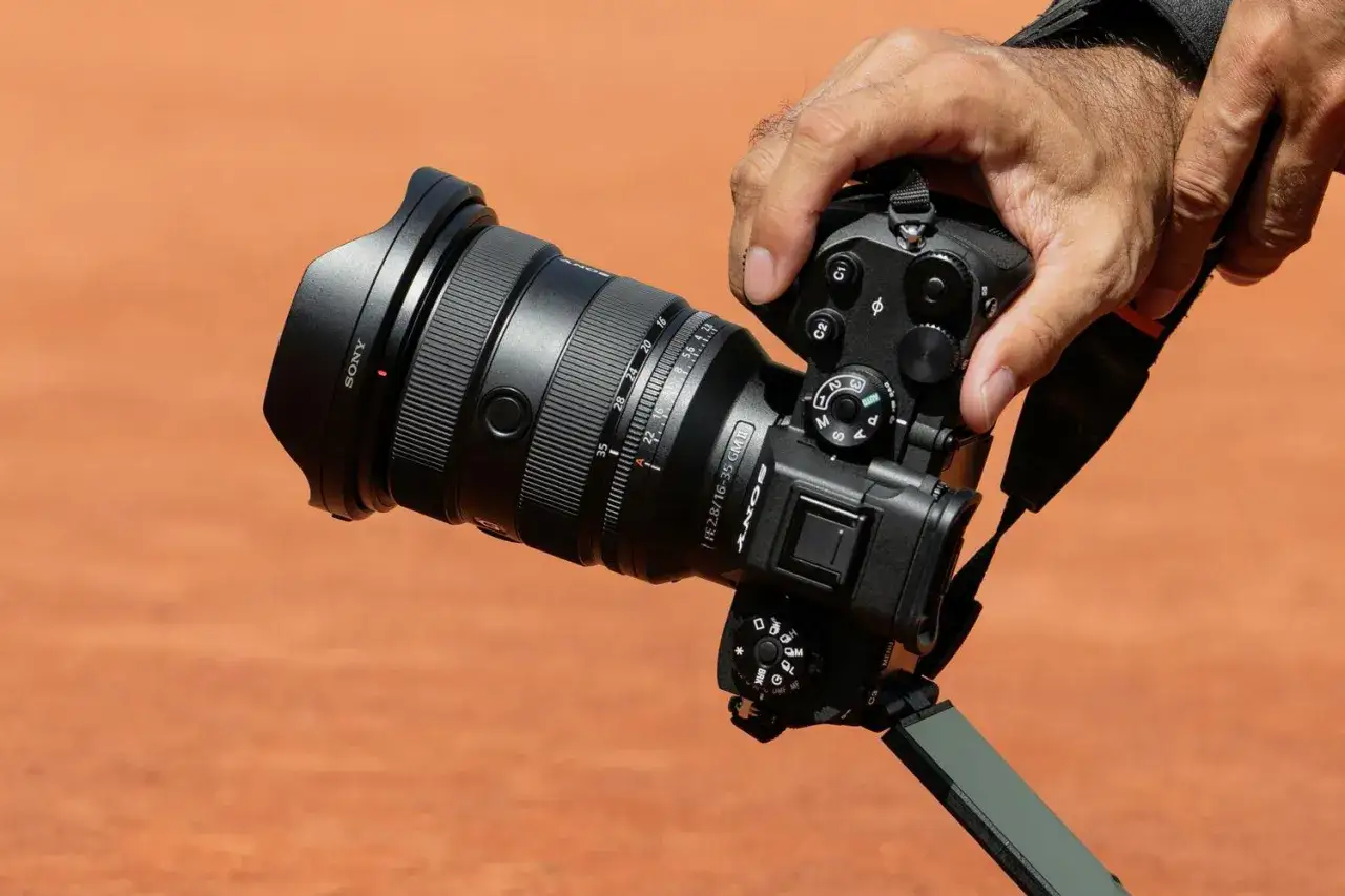 En hand håller en Sony a9 III med ett stort objektiv. Kameran är redo att fånga ögonblicket.