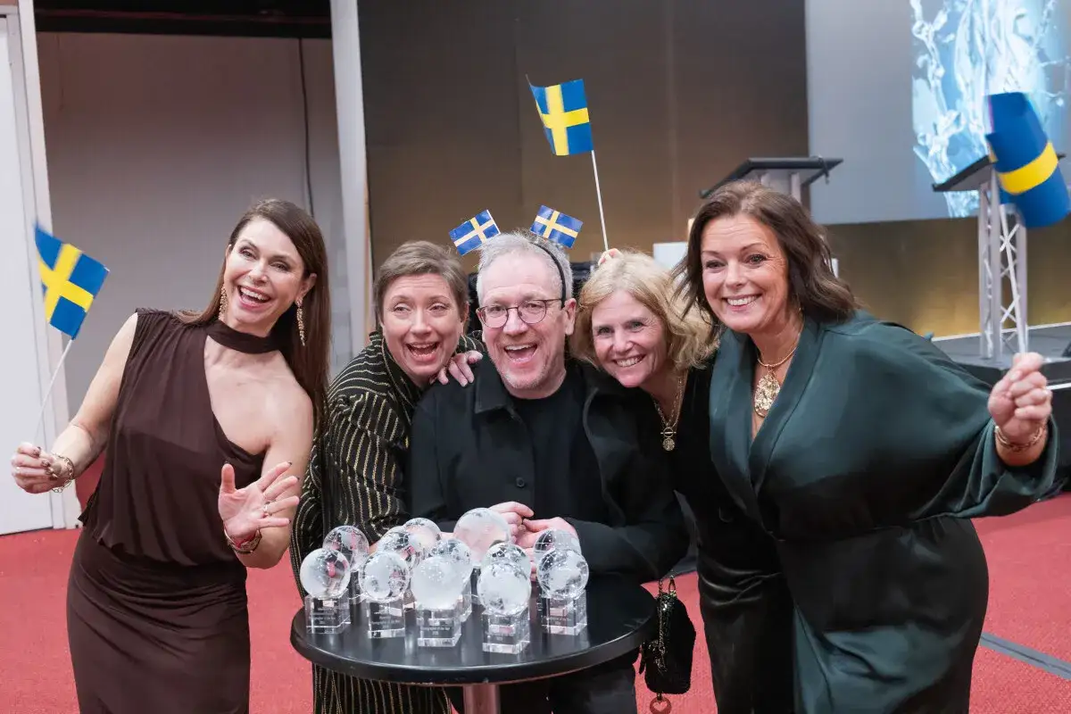 Glada vinnare med svenska flaggor och priser. En av dem är årets fotograf, firar stort!
