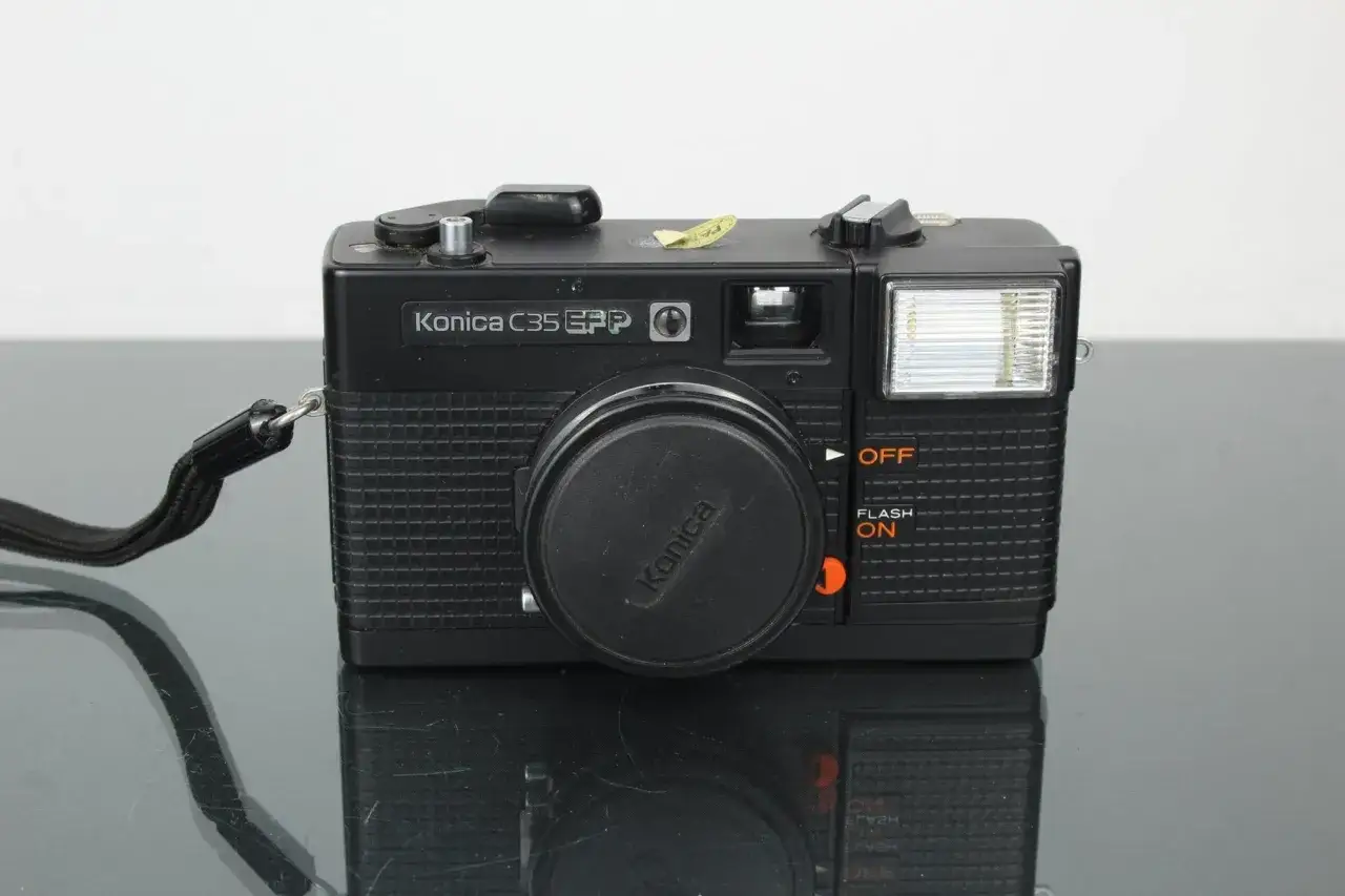 Svart Konica C35 EFP-kamera med blixt och objektivlock. Perfekt f&ouml;r att f&aring;nga klassiska &ouml;gonblick.