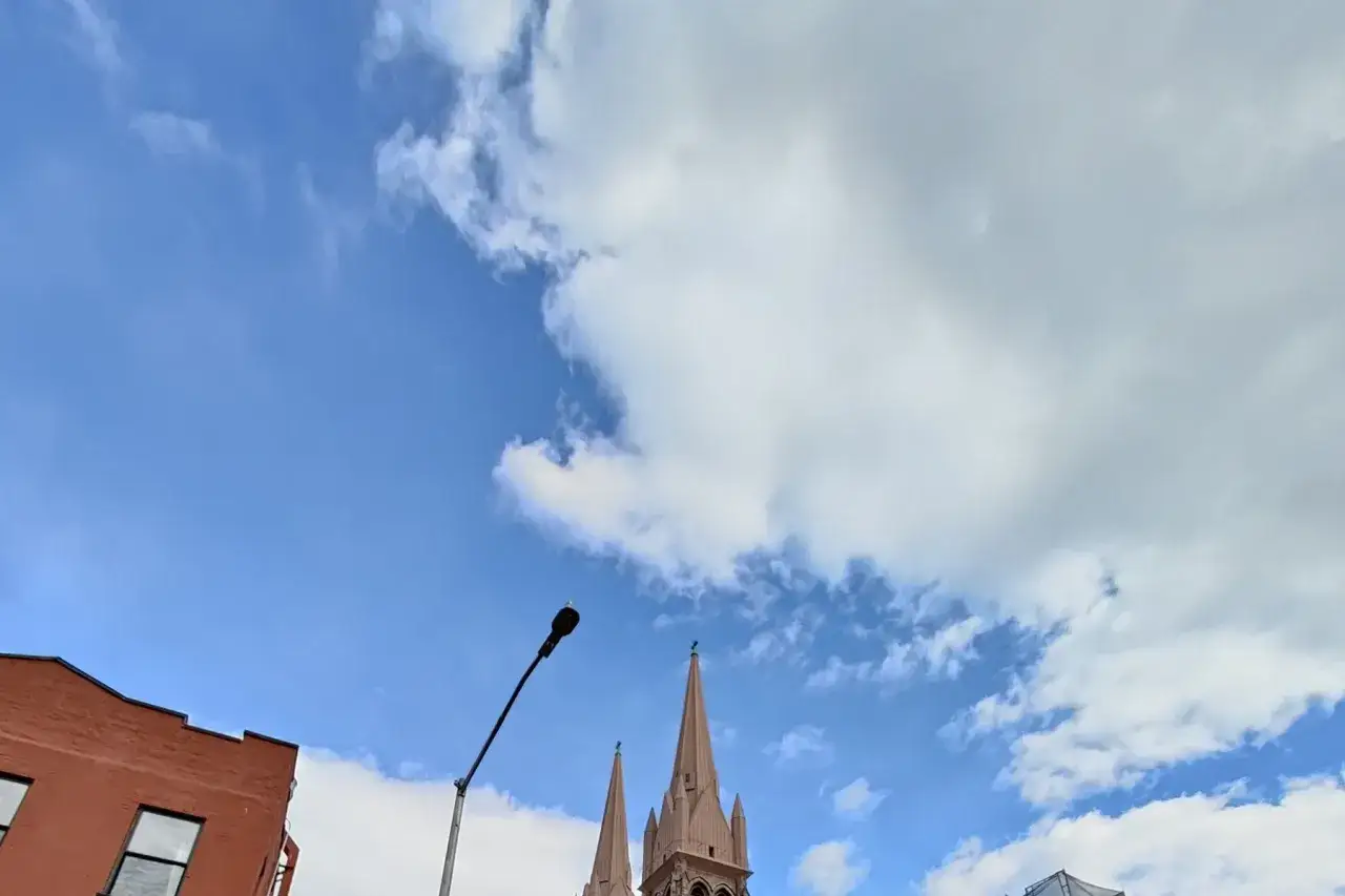 Molnigt himmel med kyrktorn och en lyktstolpe. En oneplus 10 pro test av himlen.