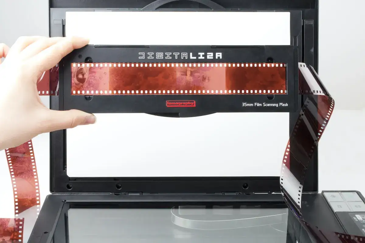 En hand placerar en 126 filmremsa i en skanner.