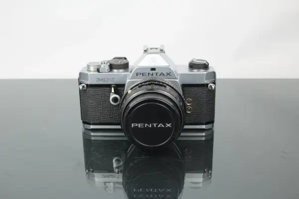 En klassisk Pentax MX-kamera med objektivlock.