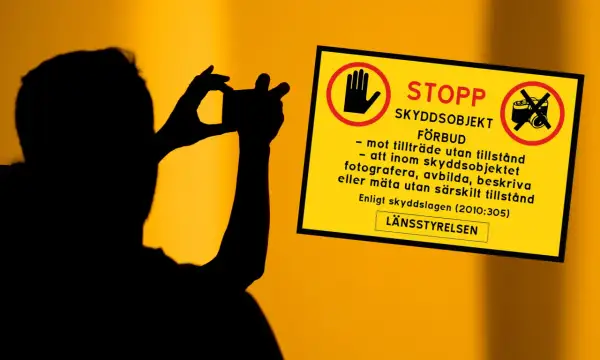 Silhuett av person som fotograferar. Gul skylt med texten "STOPP SKYDDSOBJEKT FÖRBUD" och symboler som varnar för att fotografera, avbilda eller mäta utan tillstånd.