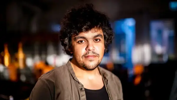 Alexander Mahmoud, en ung man med lockigt mörkt hår och skäggstubb, blickar mot kameran.