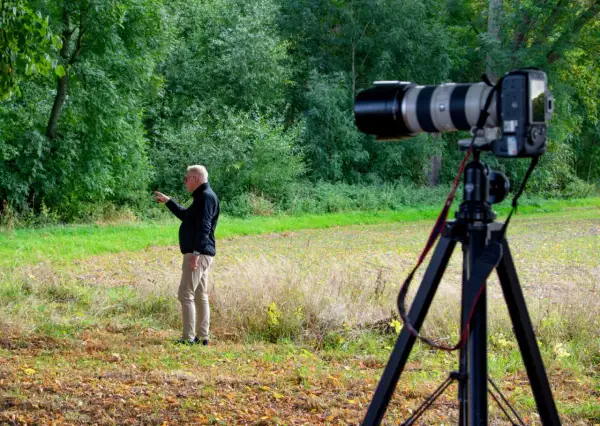 Man pekar i skogen. En kamera på stativ är redo för bildanalys.