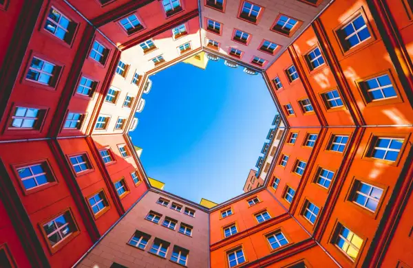 Fasaderna på ett färgglatt hus bildar en cirkel runt en klarblå himmel. Fönstren är många och speglar ljuset. En vacker vy att skapa bild av.
