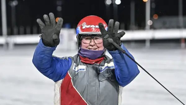 Jenny Rehnman vinkar glatt med båda händerna, klädd i tävlingskläder och hjälm.